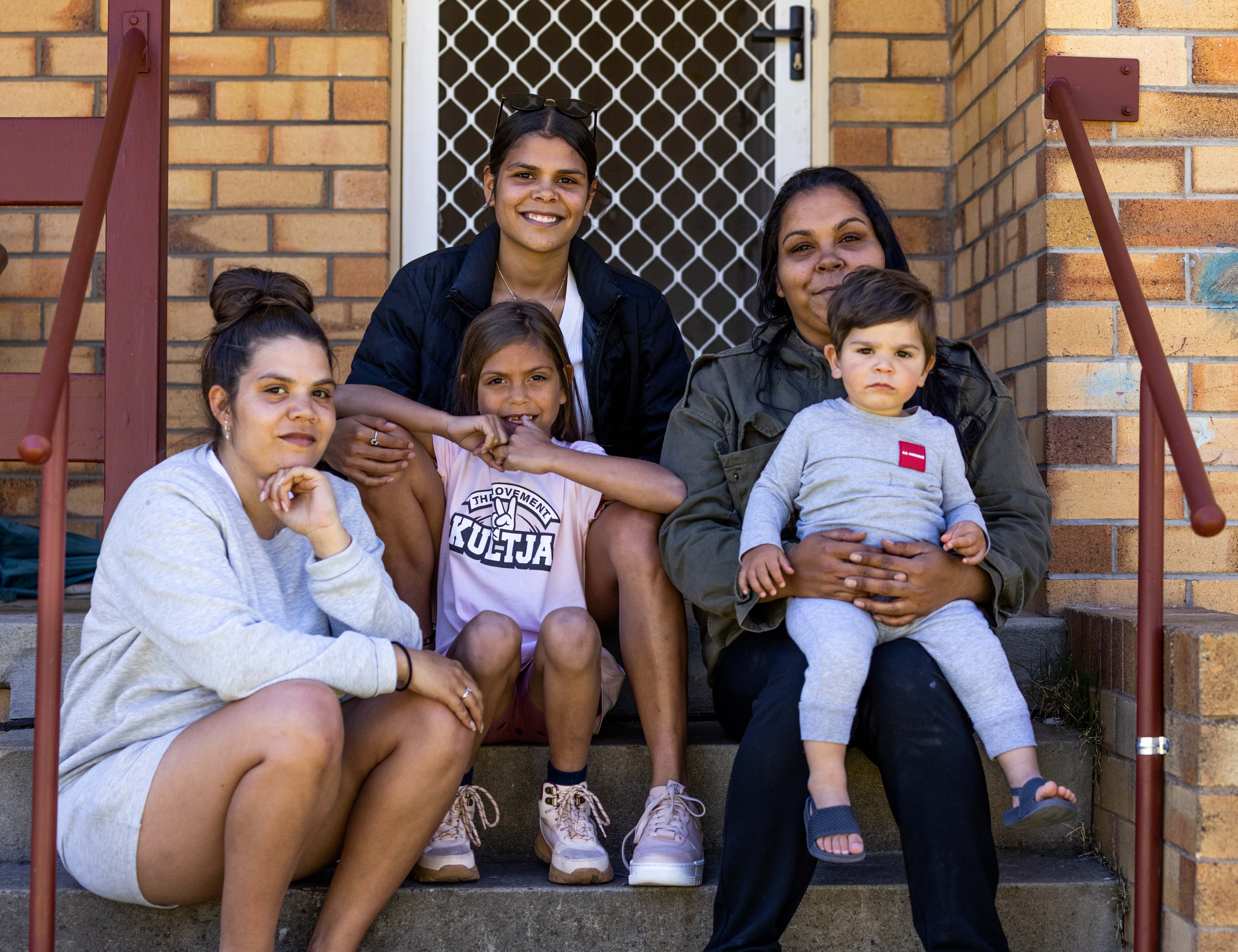 Photo of a family who are AHO tenants on the steps of their home